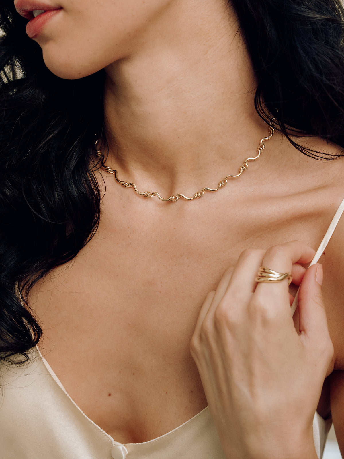 A gold necklace from the SEEN collection worn at the collarbone